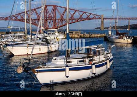 Barche ormeggiate nel porto di South Queensferry con lo sfondo di Forth Rail Bridge - South Queensferry, Scozia, Regno Unito Foto Stock