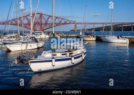 Barche ormeggiate nel porto di South Queensferry con lo sfondo di Forth Rail Bridge - South Queensferry, Scozia, Regno Unito Foto Stock