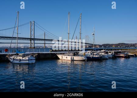 Neve sulla banchina nel porto di South Queensferry con sfondo di Forth Road Bridge e Queensferry Crossing - South Queensferry, Scozia, Regno Unito Foto Stock