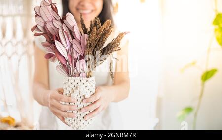 Femmina Hand Holding Macrame Plant Hanger con filo beige, arredamento vintage boho stile. Decorativo in-house. Foto Stock