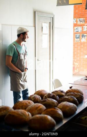 Il panettiere giovane mostra il suo pane artigianale. Concetto di successo, finale. Foto Stock