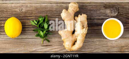 Banner di zenzero radice limone menta e miele ingredienti per bevande calde naturali su sfondo di legno. Spazio copia Foto Stock