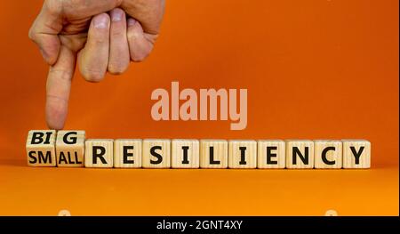 Simbolo di resilienza grande o piccolo. Businessman trasforma i cubi di legno, cambia le parole piccola resilienza a grande resilienza. Bellissimo sfondo arancione, copia sp Foto Stock