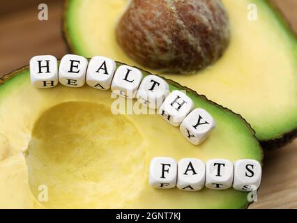avocado halfed maturo con testo da lettere a cubetti, concetto di grassi sani Foto Stock