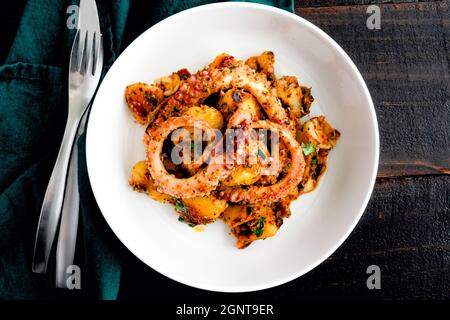Polpo spagnolo con patate: Polpo tenero servito con patate rosolate e peperoni gialli dolci Foto Stock