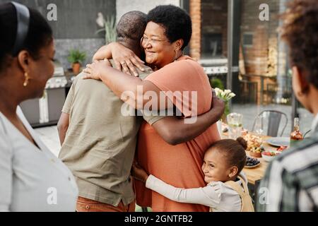 Vita in su ritratto di matura donna afroamericana abbracciando l'amico durante la riunione della famiglia al partito di cena all'aperto, spazio di copia Foto Stock