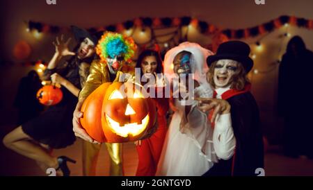 Gruppo di amici adulti con una lanterna jack-o-lanterna che si diverte in un party in costume a casa Foto Stock