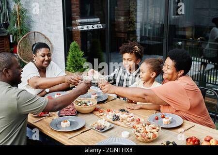 Ritratto di grandi occhiali da sole della famiglia afroamericana mentre si gusta la cena insieme all'aperto e festeggiamenti Foto Stock