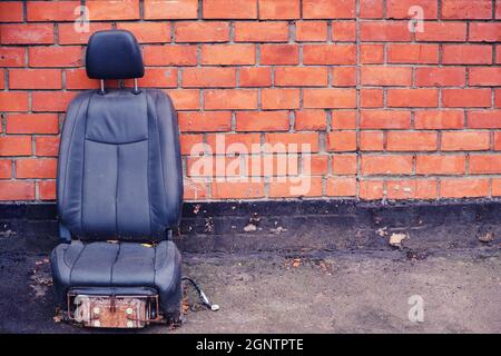 Una vecchia sedia di cuoio del boss con tappezzeria ragged, concetto di fallimento e problemi di affari. Muro di mattoni rossi con posto per testo, spazio di copia Foto Stock