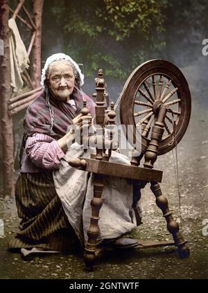 Un XIX secolo, quintessential fotocrom di una vecchia donna filare filo su una ruota tradizionale filatura. Foto Stock