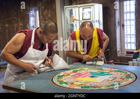 I monaci buddisti tibetani creano un mandala di sabbia a mano durante un evento alla Old City Gaol nel quartiere storico di Charleston, South Carolina. La complessa opera d'arte, che richiede diversi giorni, viene smantellata al termine Foto Stock