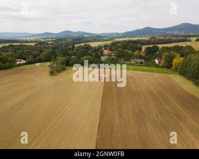 Foto aerea di un trattore che aratura un campo stoppia in campagna. Il trattore agricolo aratri terreno per la semina. Vista dall'alto dal drone . Foto Stock