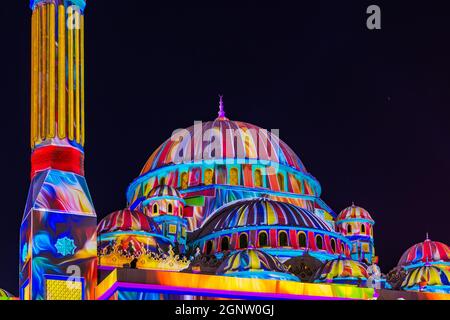 Cupola colorata e minareto della moschea di Sharjah contro il cielo scuro durante il festival della luce negli Emirati Arabi Uniti Foto Stock