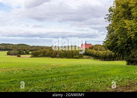 Il castello di Tranekær è rosso acceso nel parco. Il castello esiste su questo sito dal 13 ° secolo ed è stato utilizzato come residenza ufficiale dai funzionari del re danese sull'isola di Langeland, Danimarca Foto Stock