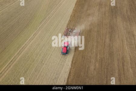 Foto aerea di un trattore che aratura un campo stoppia in campagna. Il trattore agricolo aratri terreno per la semina. Vista dall'alto dal drone . Foto Stock