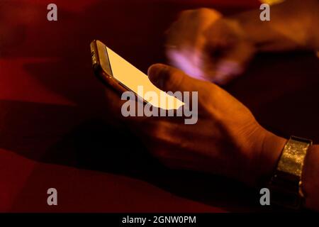 donna che utilizza applicazioni per telefoni cellulari nel bel mezzo della notte a un tavolo in un bar Foto Stock