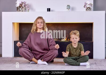 Il ragazzo di 6 anni fa esercizi di yoga con la madre a casa. Foto Stock