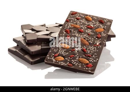 Cioccolato fondente crudo con mandorle e bacche di goji su sfondo bianco. Isolare Foto Stock