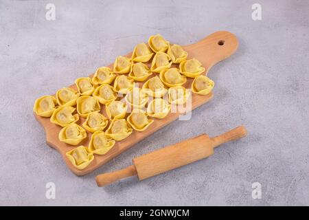 Tortelloni non cotti con farcitura di funghi su tavola di legno. Cucina italiana Foto Stock