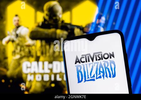 Logo Activision Blizzard sullo schermo dello smartphone. Una cornice di Call of Duty sullo sfondo. Foto Stock