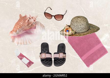 Accessori da spiaggia donne. Cappello di paglia e asciugamano, infradito o sandali da spiaggia, occhiali da sole, crema solare e una conchiglia su sfondo chiaro sfocato. Viaggi Foto Stock