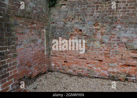 Vecchio angolo giardino in mattoni stagionato con ghiaia a terra Foto Stock