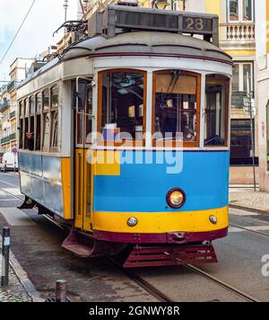 Tram d'epoca in una strada lastricata della città vecchia di Lisbona con architettura tipica, il Portogallo Foto Stock