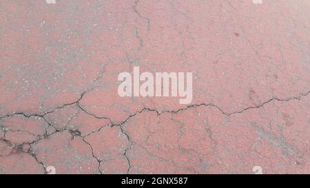 Strada danneggiata di colore rosso o sentiero lastricato con scricchioli di stanghette diverse. Trama incrinata con spazio di copia per testo e messaggi Foto Stock