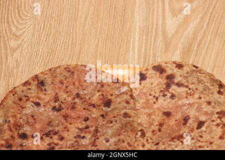 Paratha tradizionale - closeup macro con fuoco selettivo di pane oleoso fatto in casa o parotta su un piatto su pavimento di legno. Chapati è cibo tradizionale di Foto Stock