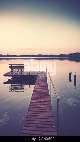 Molo lago in legno con panca al tramonto, tonificante applicato. Foto Stock