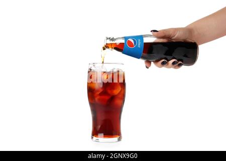 Odessa, Ucraina - 23 settembre 2021: Mano femminile versare Pepsi da bottiglia a vetro, isolato su sfondo bianco. Foto Stock