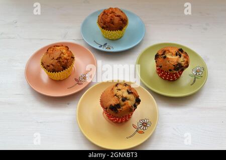 Deliziosi cupcake di compleanno sul tavolo su piatti colorati e sfondo chiaro Foto Stock