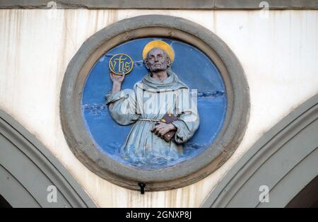 San Bernardino da Siena, vetrato tondo in terracotta di Andrea della Robbia, situata tra due archi del vecchio Ospedale di San Paolo, a Firenze, Ita Foto Stock