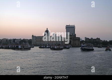 Taj Mahal Hotel, Gateway of India e barche turistiche in acqua del Mar Arabico al tramonto a Mumbai, India Foto Stock