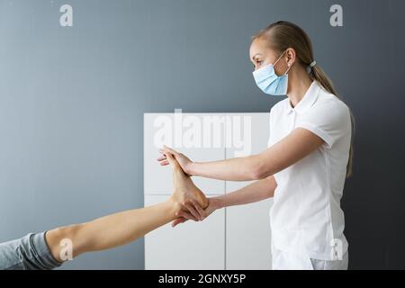 Agopuntura Donna piedi Massaggio e trattamento di terapia del dolore in faccia Maschera Foto Stock