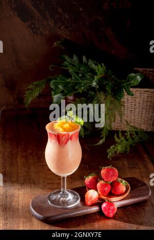 Tazza di fragola, mango e succo di foglie di menta su tavola di legno Foto Stock