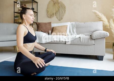 Giovane donna yoga che pratica meditating a casa. Immagine meditazione yoga con spazio copia Foto Stock