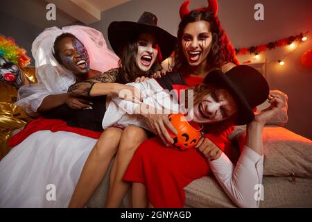 Giovani uomini e donne vestiti in costumi che si divertono a una follia festa di Halloween Foto Stock