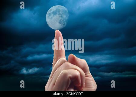 mano della donna con punti indice del dito e sebra per sostenere la luna Foto Stock