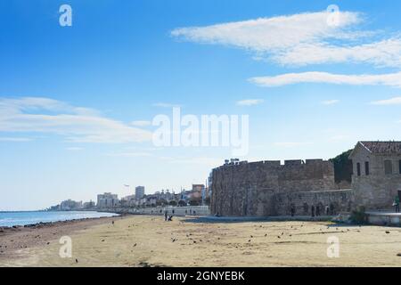 LARNACA, CIPRO - 17 FEBBRAIO 2019: Persone che camminano al resort argine di Larnaca, Laranaca Castello e forte sullo sfondo Foto Stock