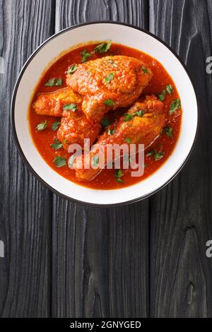 Ayam masak merah è un piatto tradizionale malese è una casseruola di pezzi di pollo in peperoncino sambal secco primo piano in una ciotola sul tavolo. Vertica Foto Stock