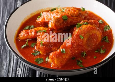 Ayam masak merah è un piatto malese fatto con pezzi di pollo che vengono conditi in un primo piano ricco, speziato e cremoso salsa di pomodoro in una ciotola sulla teglia Foto Stock