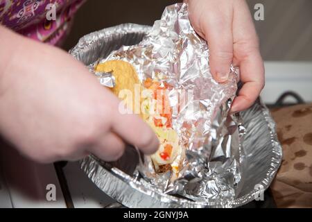 Donna che disimballa il foglio di alluminio da un paio di tacos freschi Foto Stock