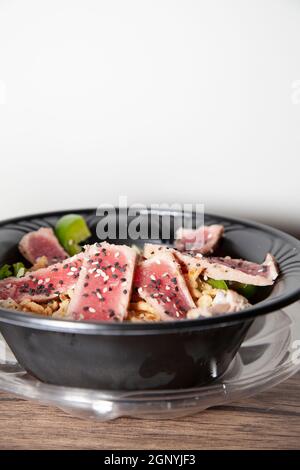 Insalata di tonno scottato con lattuga, peperone verde a fette e cipolla rossa su un tavolo di legno Foto Stock