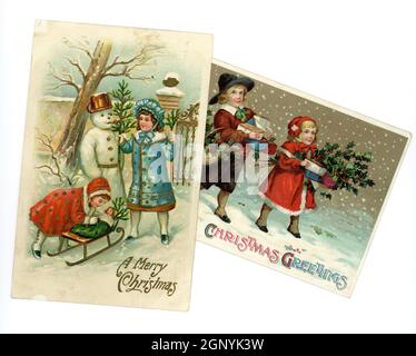 Originale in rilievo Edwardian era Natale cartoline di auguri stampate in Germania, di bambini piccoli carini che indossano abiti invernali alla moda in questo momento, costruire un pupazzo di neve e portare doni, circa 1910, Regno Unito Foto Stock