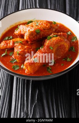 Ayam masak merah è un piatto tradizionale malese è una casseruola di pezzi di pollo in peperoncino sambal secco primo piano in una ciotola sul tavolo. Vertica Foto Stock