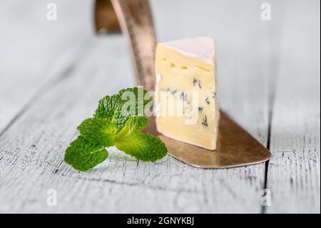 Incuneamento di formaggio blu sotto una crosta di muffa bianca Foto Stock