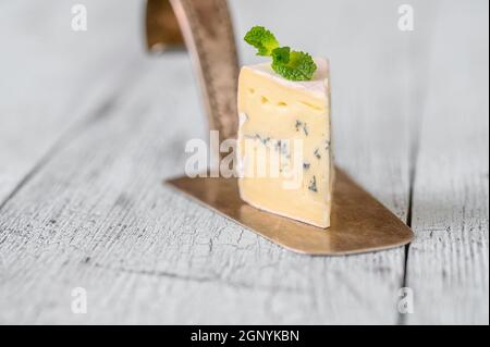 Incuneamento di formaggio blu sotto una crosta di muffa bianca Foto Stock