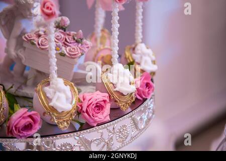 Deliziosi dessert presso il bar delle caramelle per matrimoni nell'area buffet: Torte salate decorate con angeli e cammei e boccioli di rose fresche. Spazio di copia Foto Stock