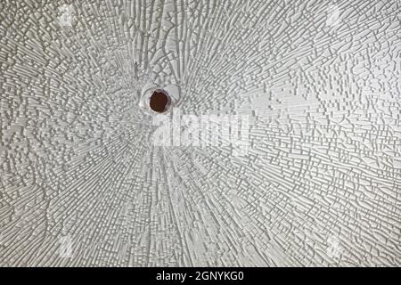 Incrinature intorno al foro nel vetro temperato rotto Foto Stock